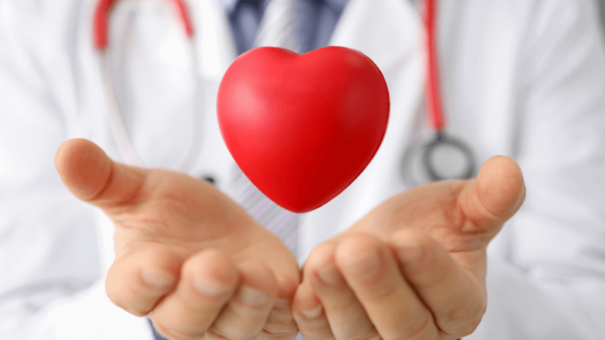 A doctor with a stethoscope, hands outstretched around a heart